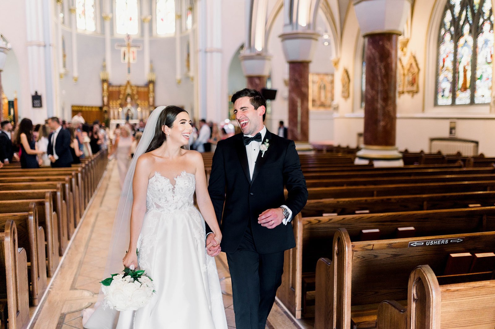 Grinning bride and groom exit church in wedding recessional. 