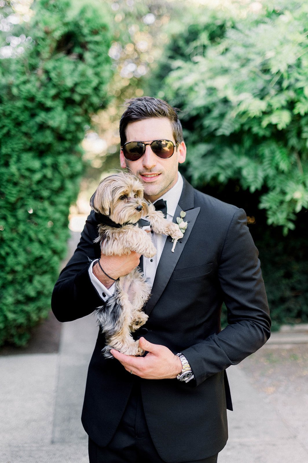 Cool looking groom cuddles Yorkie pup in matching suit at heart house wedding in Vancouver BC.