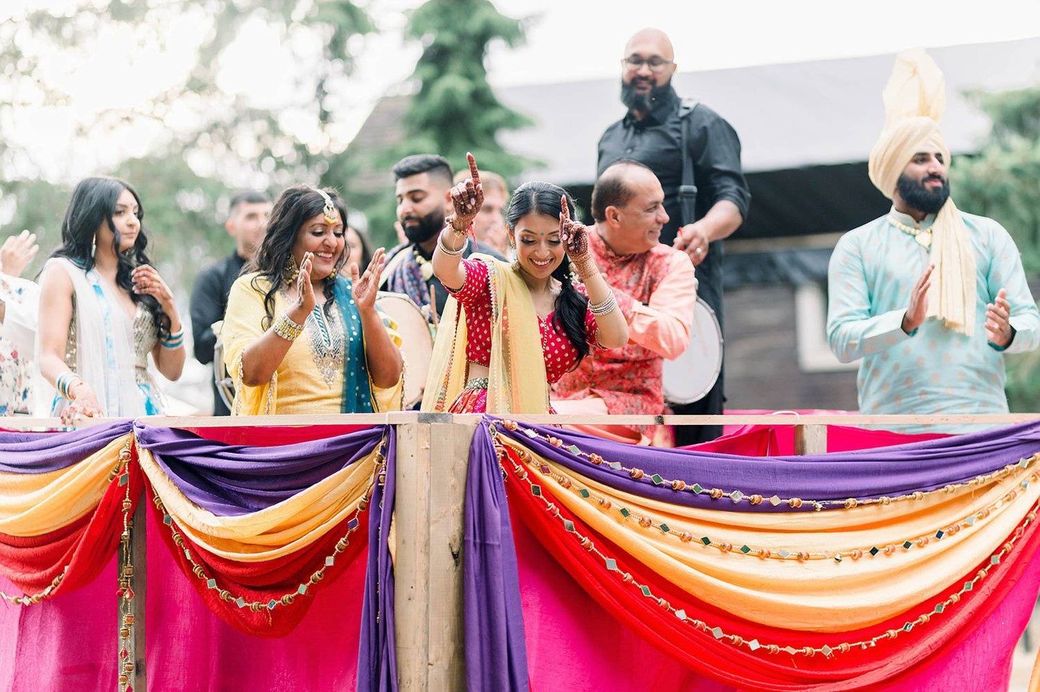 South Asian Bride and wedding guest party atop tractor as they make their entrance into the mayian ceremony. 