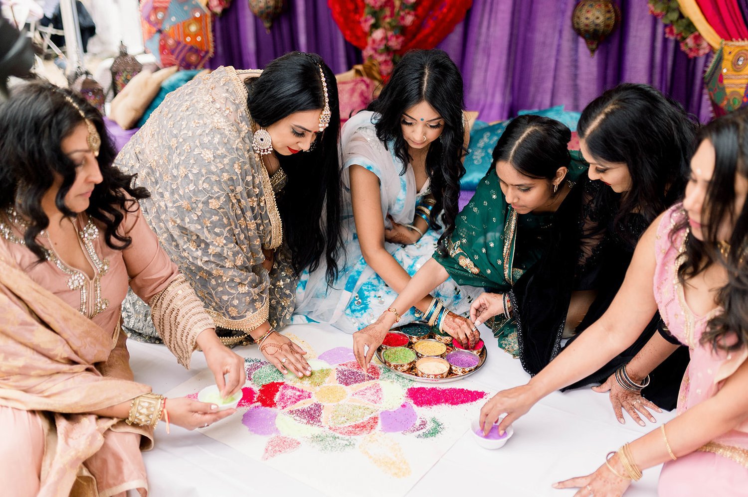 Sisters and cousins of the bride prepare rangoli for mayian ceremony.  