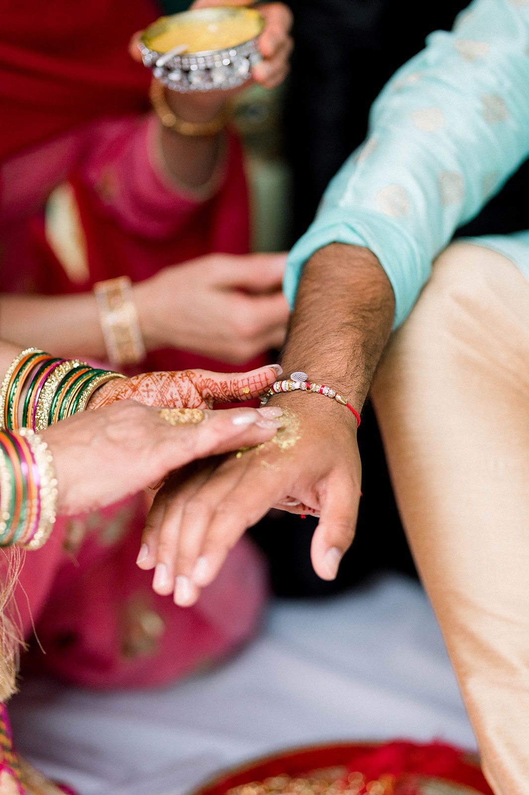 Yellow turmeric paste is smeared on grooms hand in south asian Indian wedding.