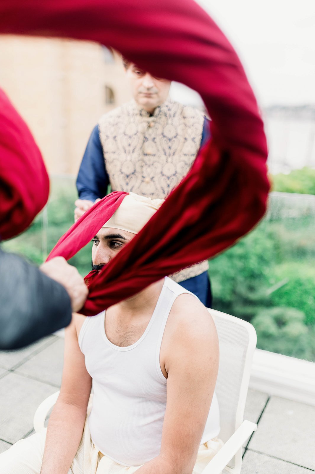 An indian groom has his red turban tied before his Sikh wedding ceremony in Victoria BC. 