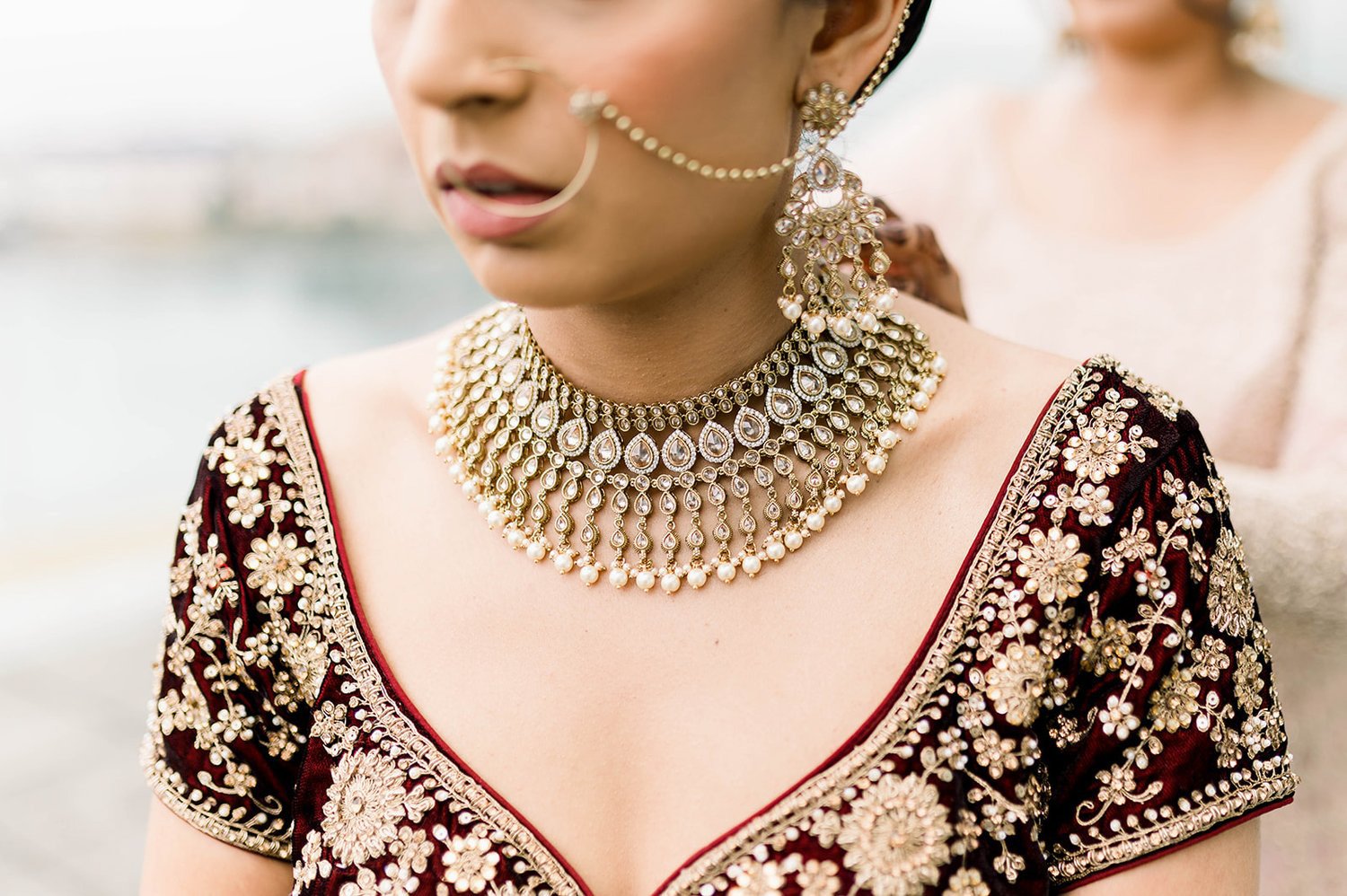 Sister of the bride drapes bride in large gold necklace on the morning of her south asian wedding ceremony in Victoria BC