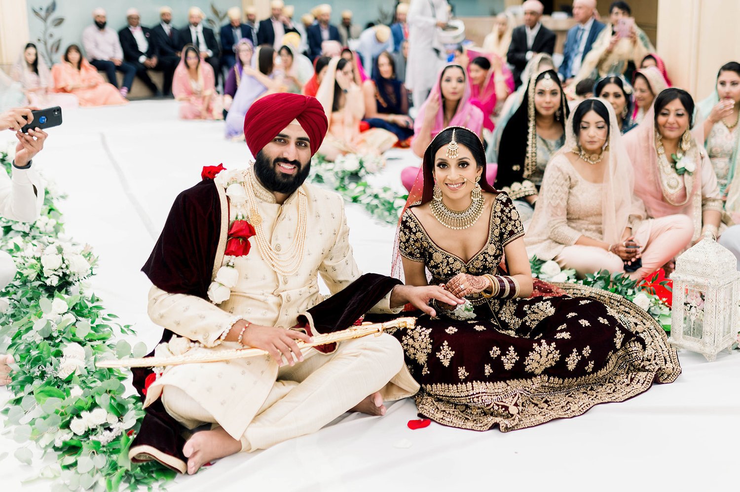 An indian bride and groom smile for the beautiful life studios photographer as they exchange rings at the end of their wedding ceremony in Victoria BC