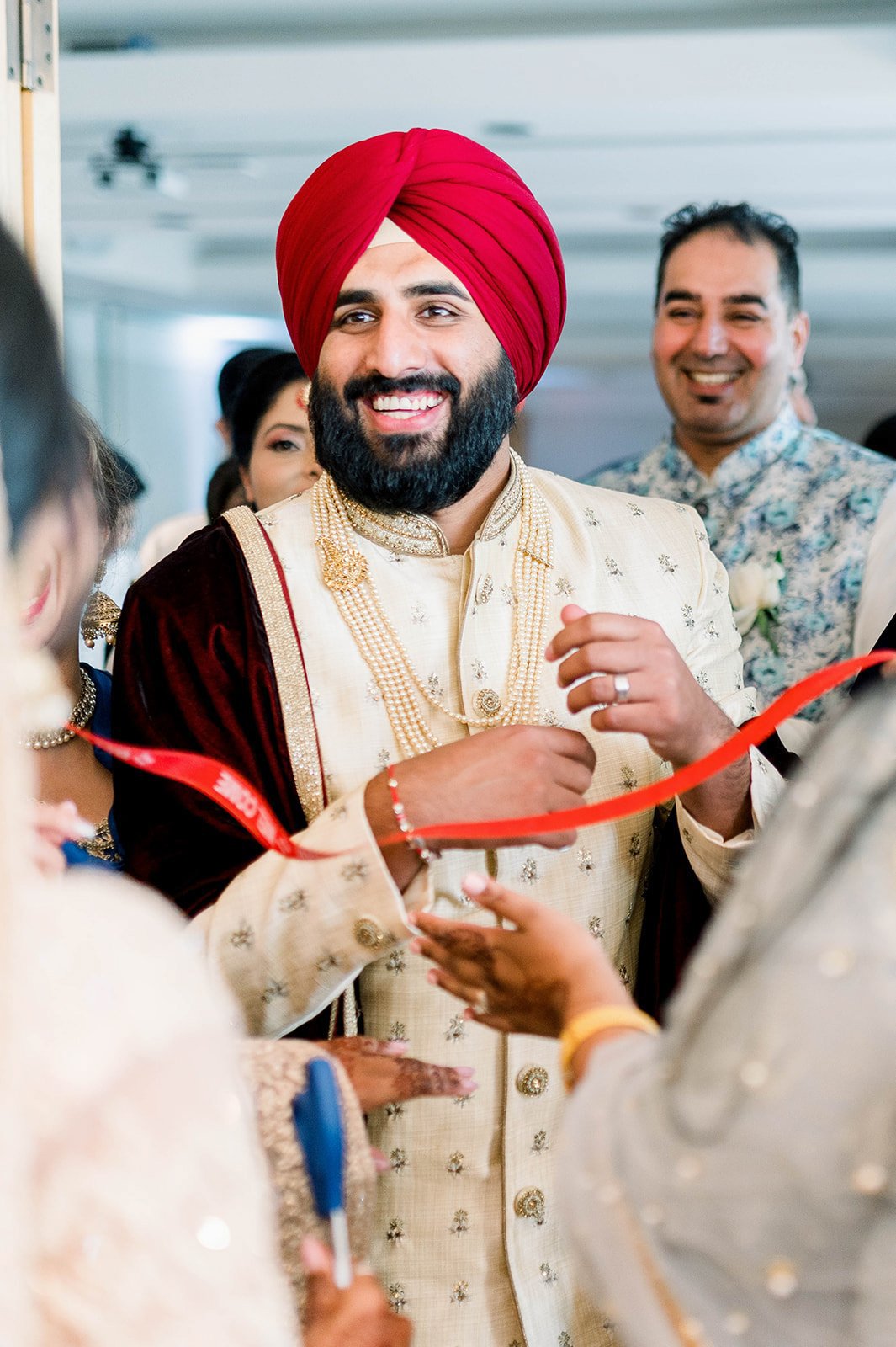 An Indian groom grins as he Bargins with the brides sisters in a doli ceremony.