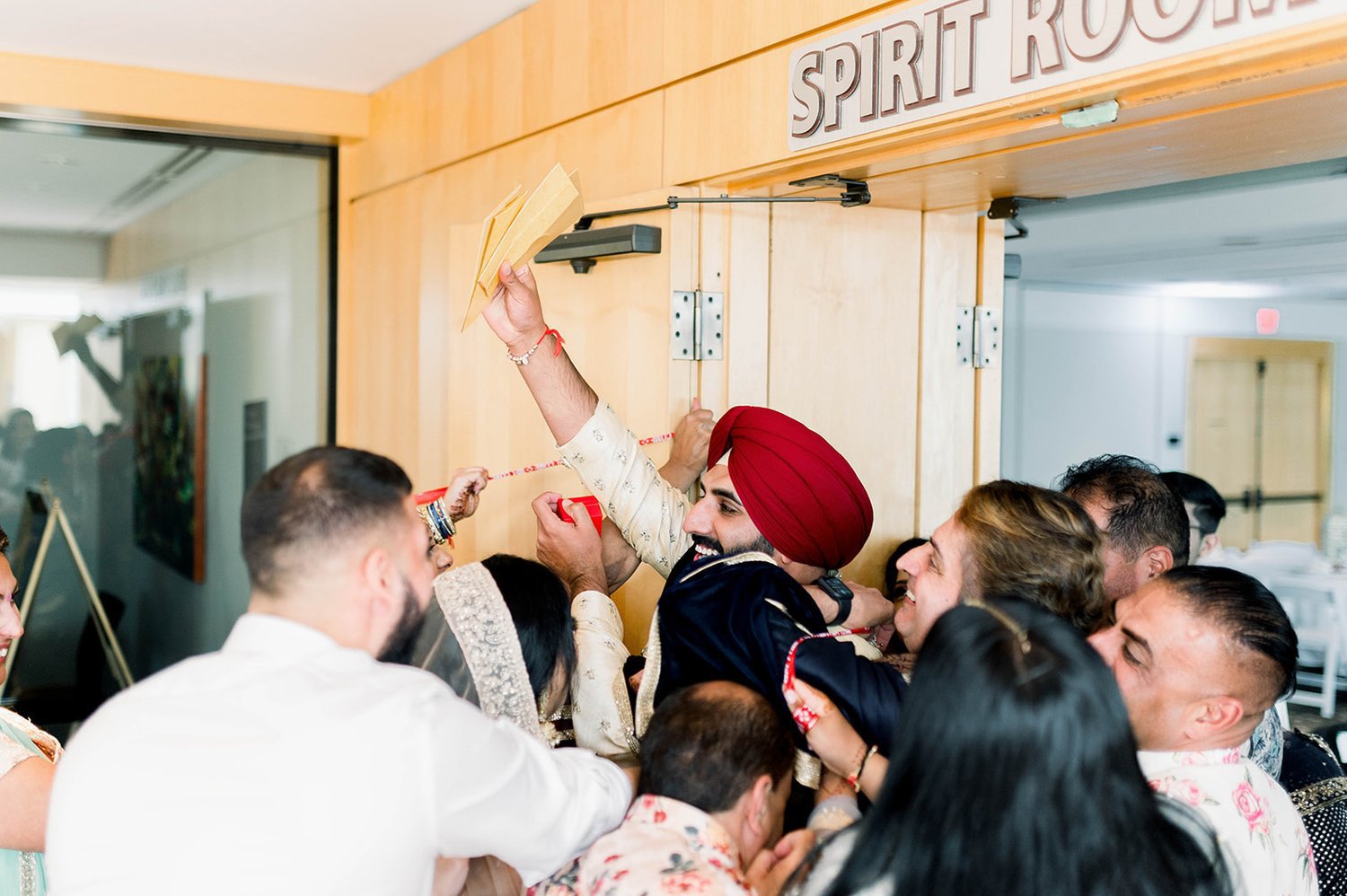 An indian groom reclaims his stolen shoes, holding one shoe up triumphantly. 