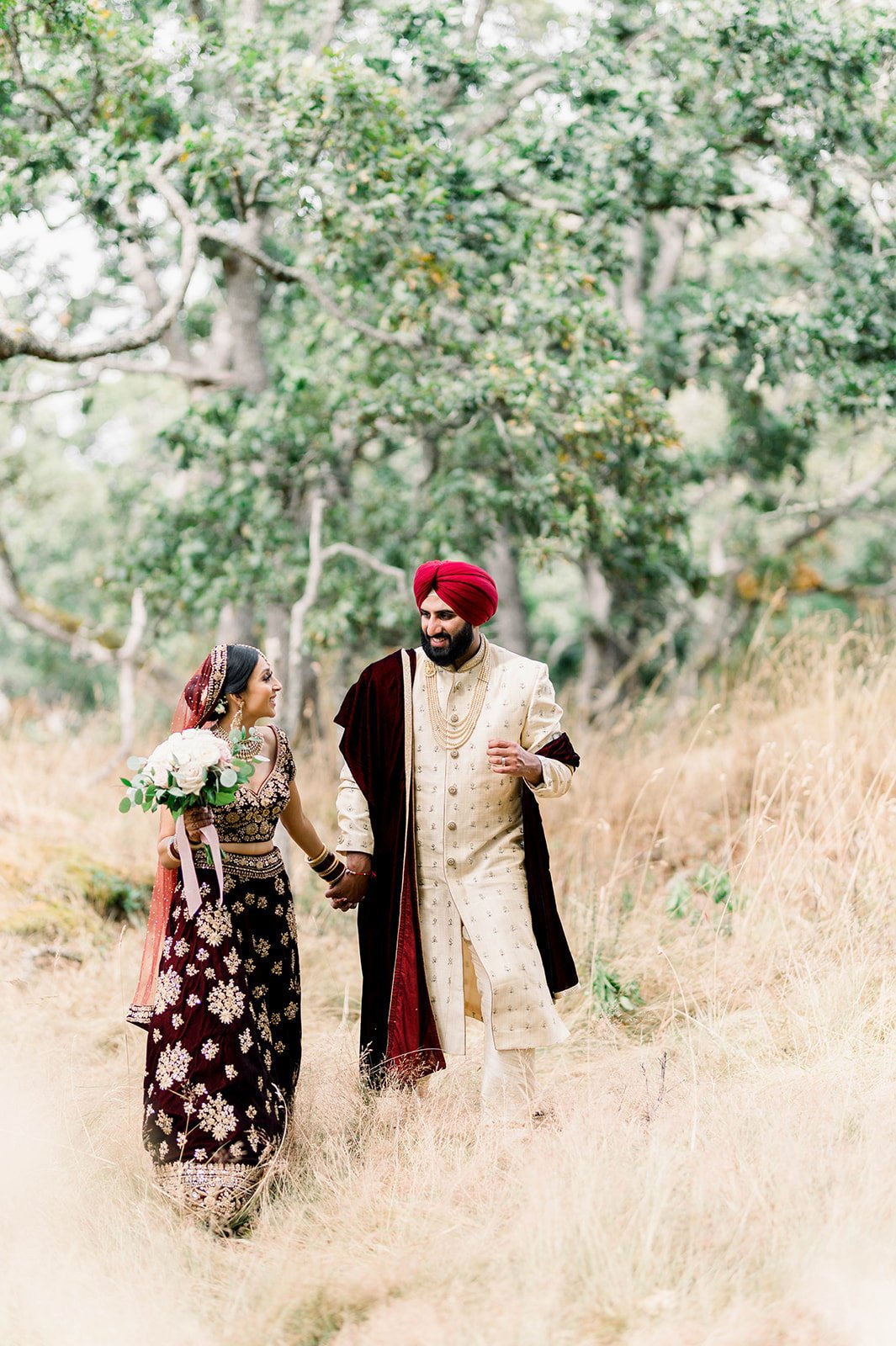 An indian groom leads his bride through romantic tall grass in Victoria BC