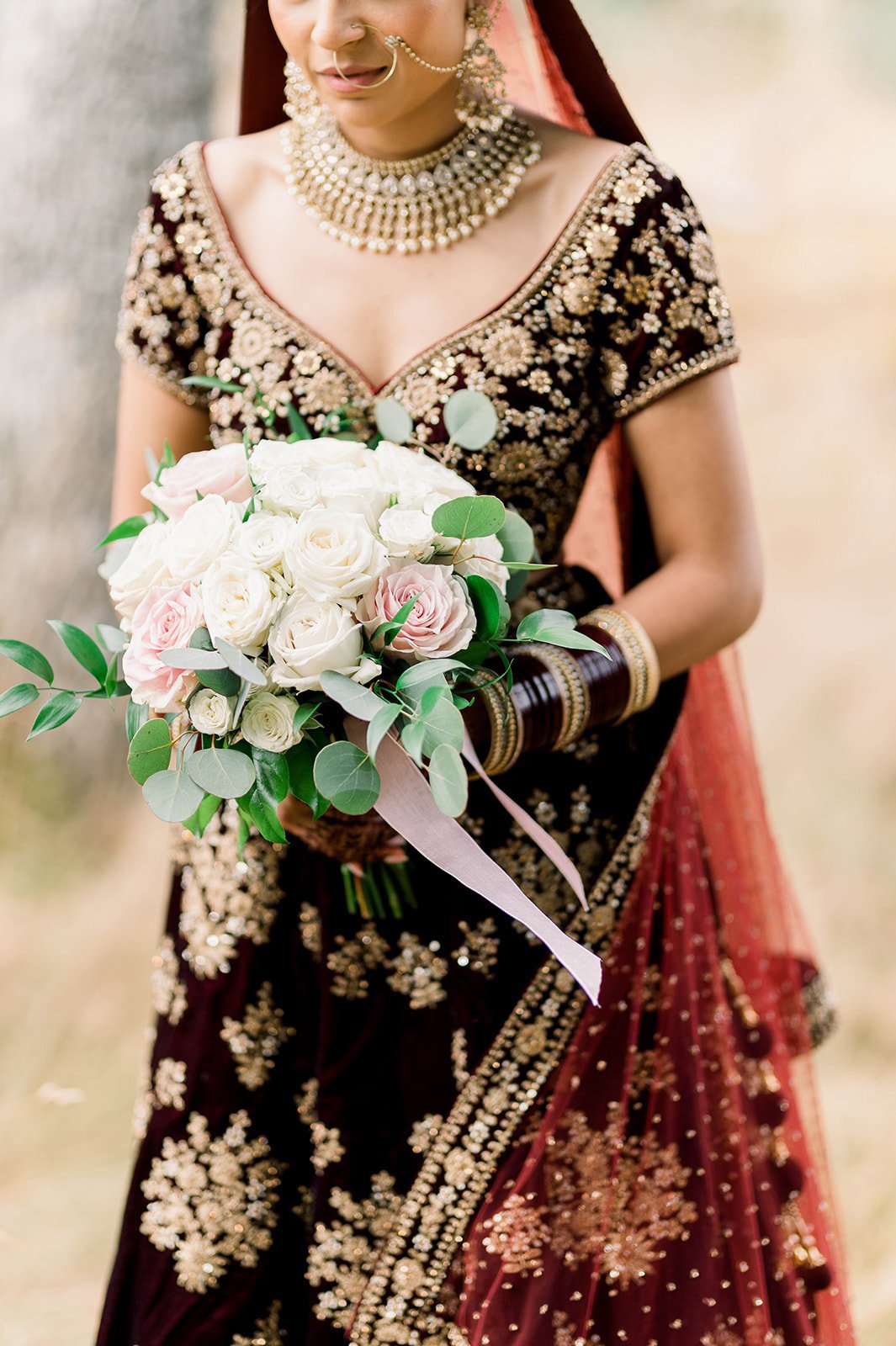 An indian bride holds a beautiful white and pink bouquet