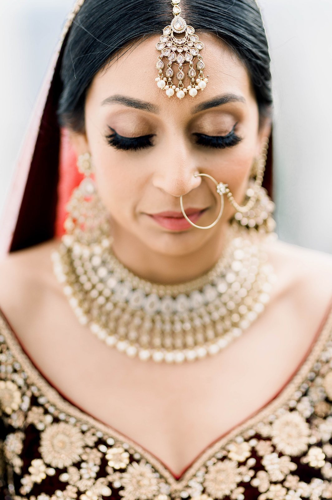 An Indian bride looks demurely towards the ground, showing off her soft brown shimmering eyeshadow 