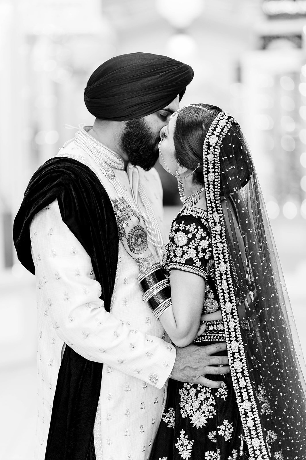 A black and white image of an indian bride and groom kissing.