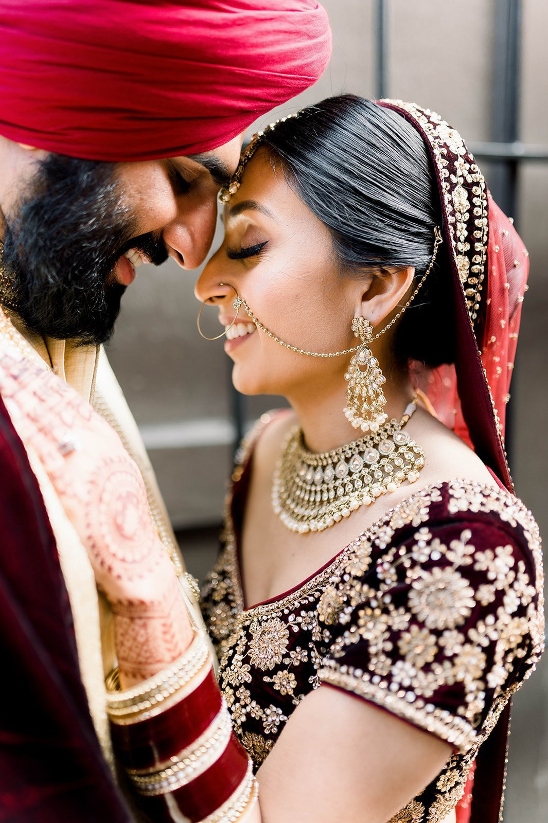 A bride and groom rest their heads together in a cuddly moment.