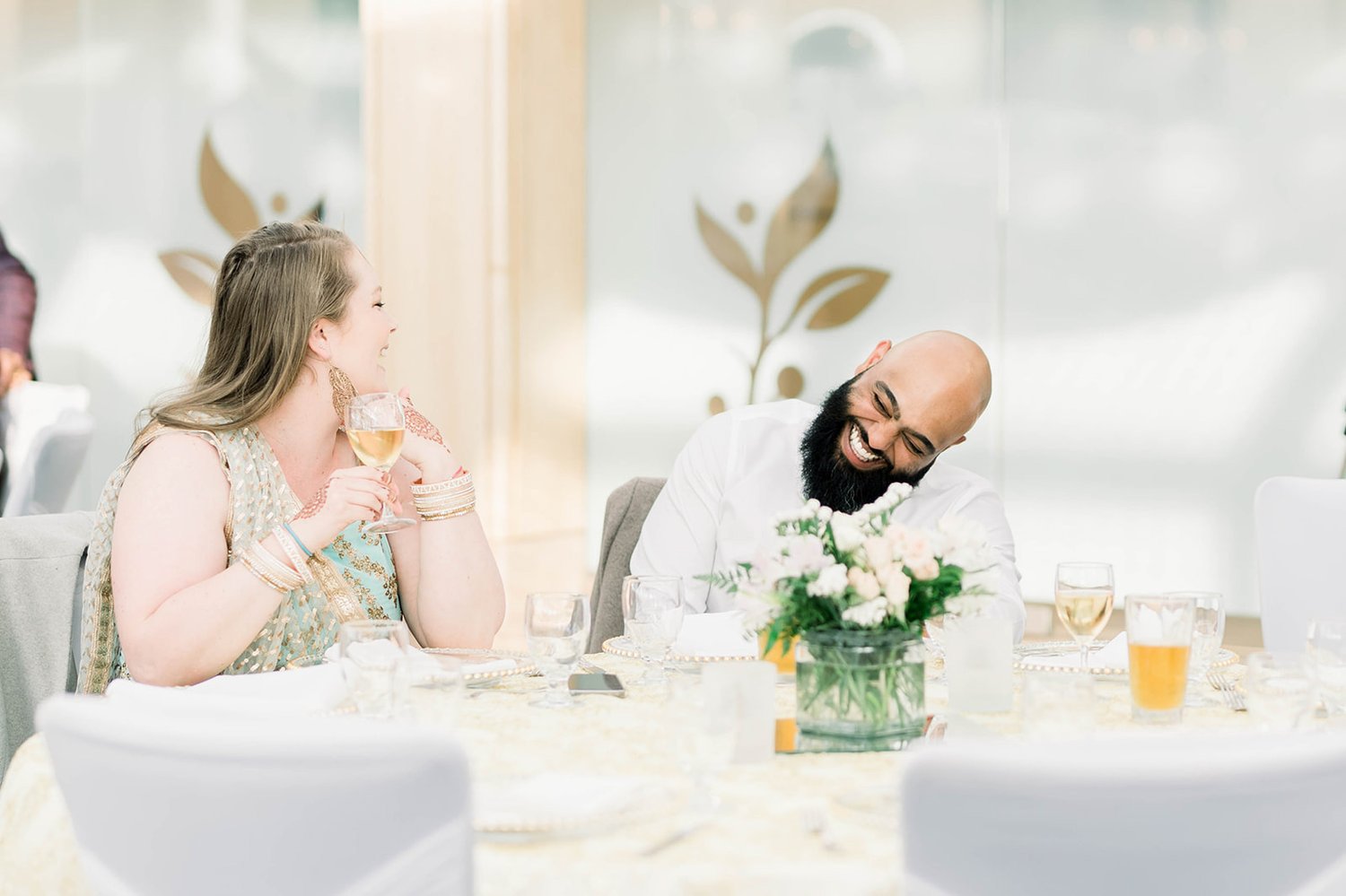 A wedding guests laughs as he sits at a table in Victoria BC 