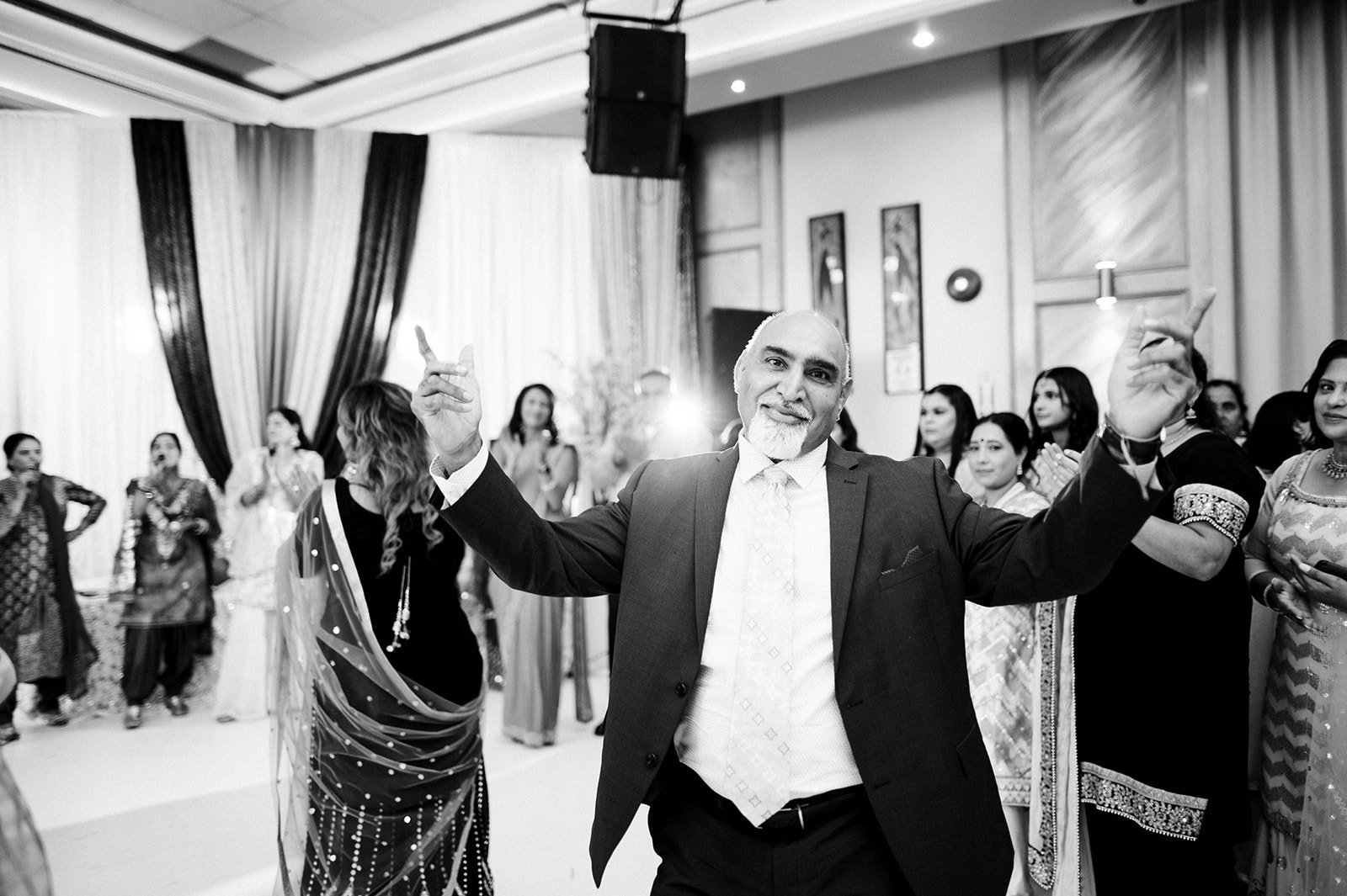 The grooms father raises his arms as he dances during his sons Jaggo ceremony in Vancouver BC  