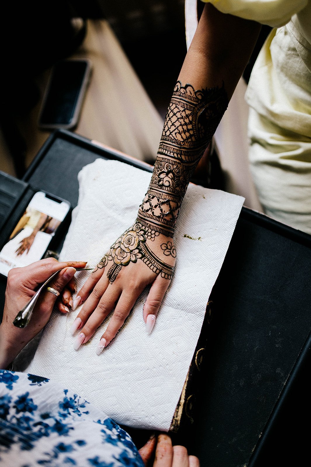 An indian bride has intricate bridal henna applied to her hand in Surrey, BC  