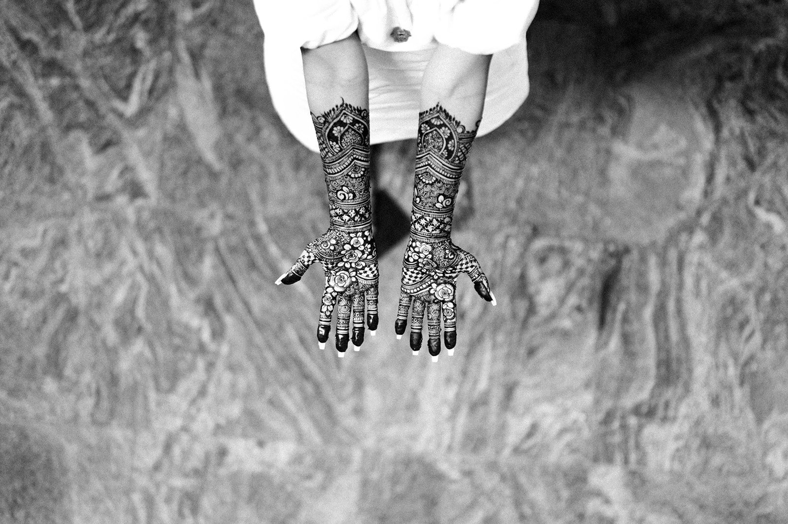 A black and white photo of two hands covered in indian bridal henna mendhi. 