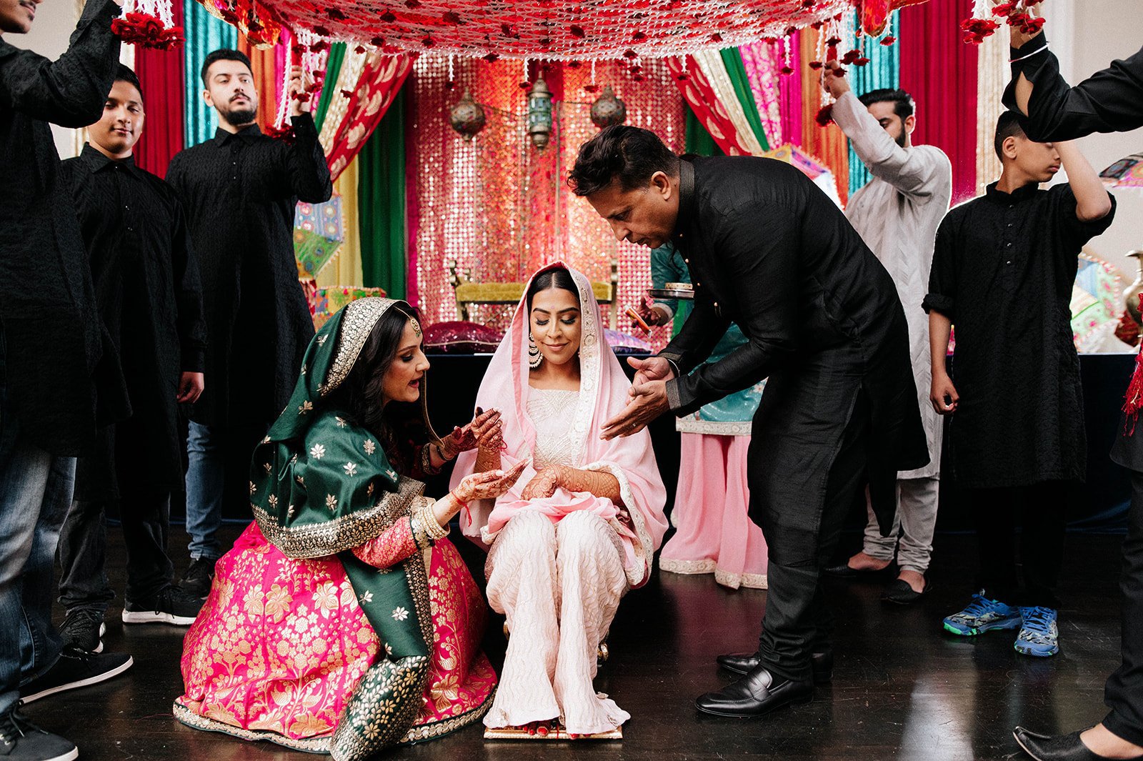 An indian bride has yellow paste applied to her arms by family members in Surrey BC 