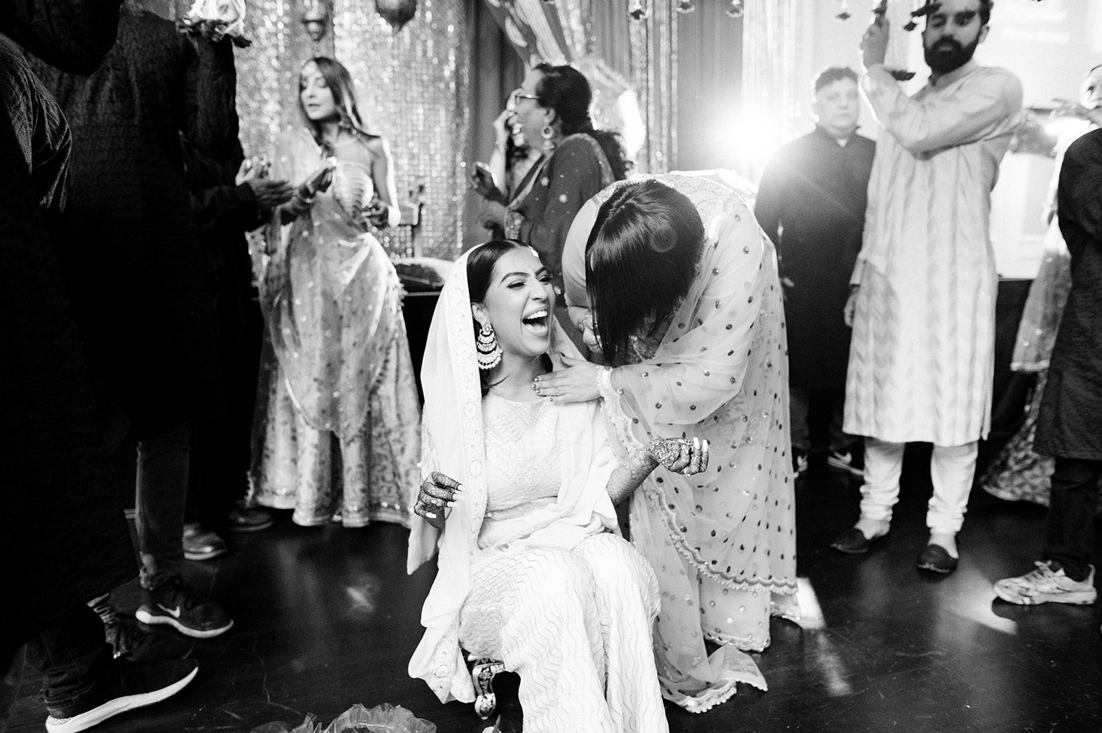 A black and white photo of a bride laughing with her friends in a Maiyan ceremony.