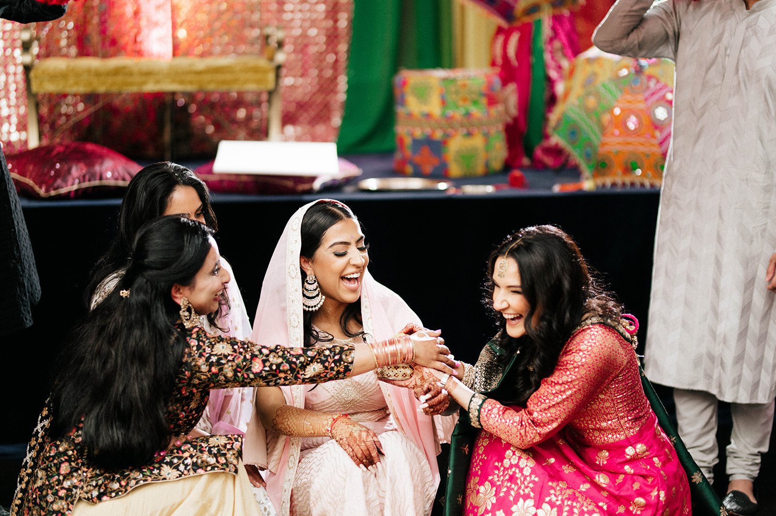 An indian bride smiles as relatives as friends apply maiyan paste to her arms in Surrey BC