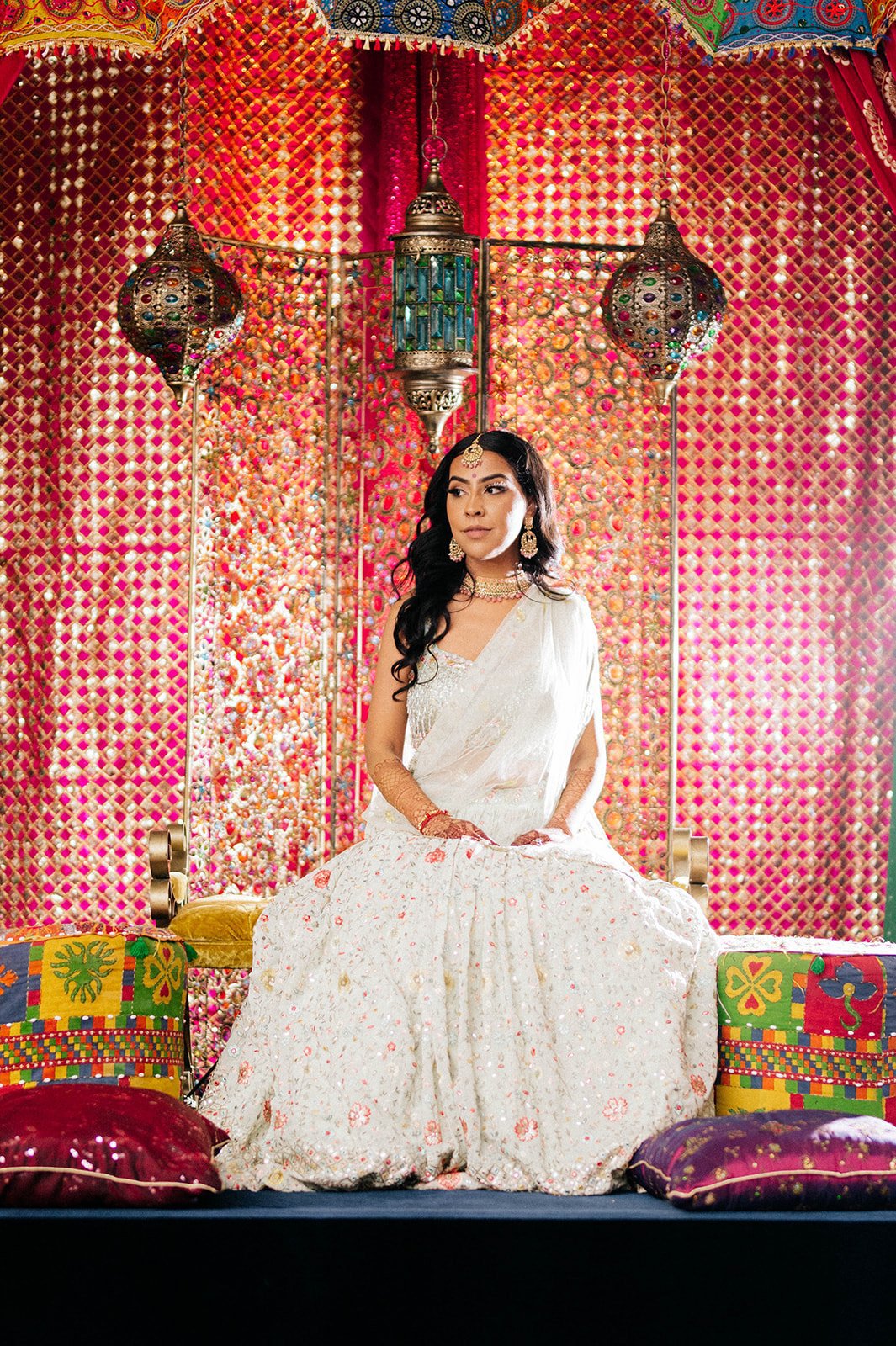 A bride poses on a stange, backlight, in a colorful mayian ceremony