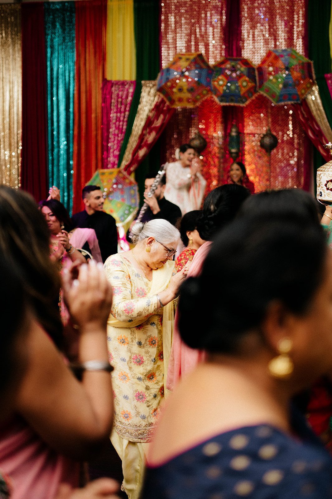 An elderly lady in traditional indian clothing  dances in a banquet hall in surrey BC. 
