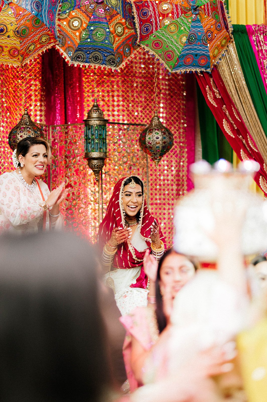 A bride in a bright red chunni smiles on stage in surrey BC 