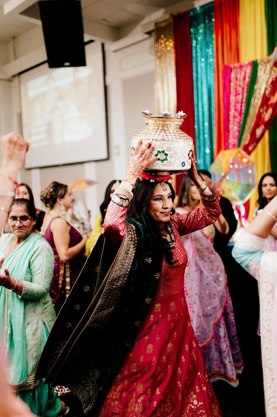 A indian woman dances with a jug on her head in an indian ceremony