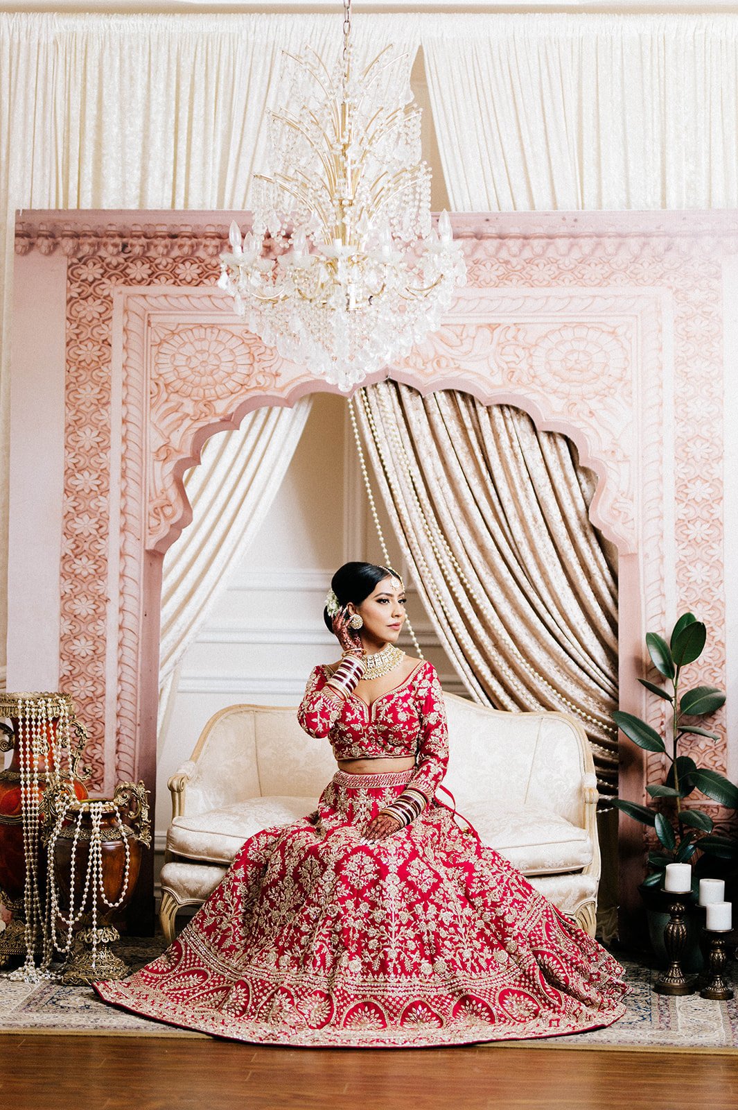 An indian bride poses on an intricate backdrop during her bridal prep. 