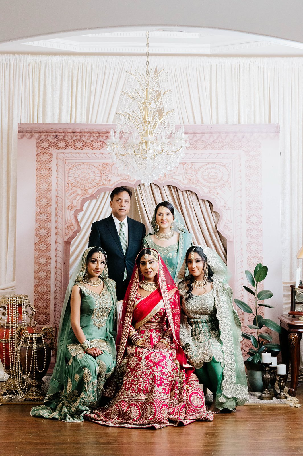 An indian family poses for a family photo in front of a tan and pink backdrop in Surrey BC 