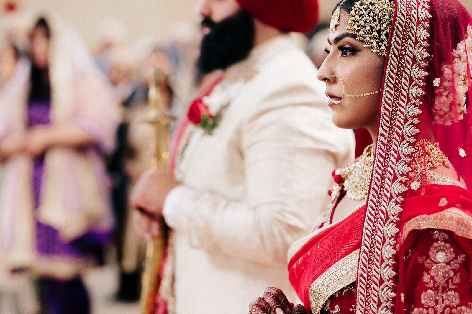 A bride looks forward thoughtfully during her Sikh wedding ceremonyl.