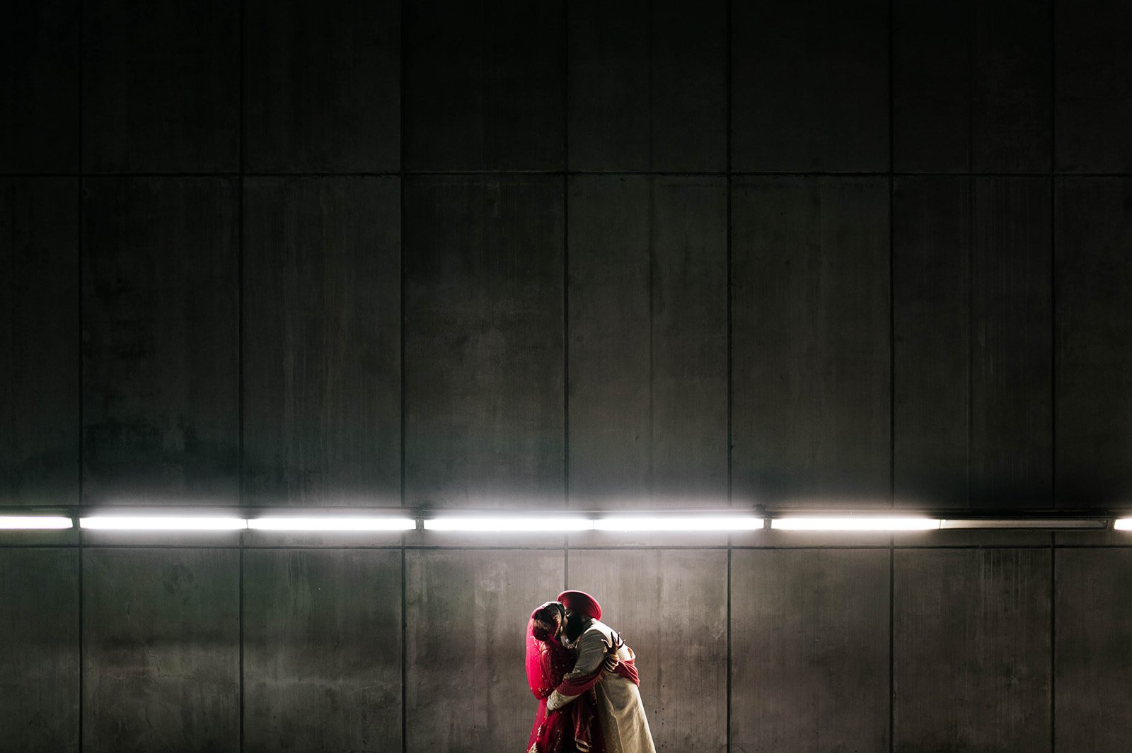 An Indian couple embrace in a cinematic backlit photo in a tunnel under vancouver, BC. 