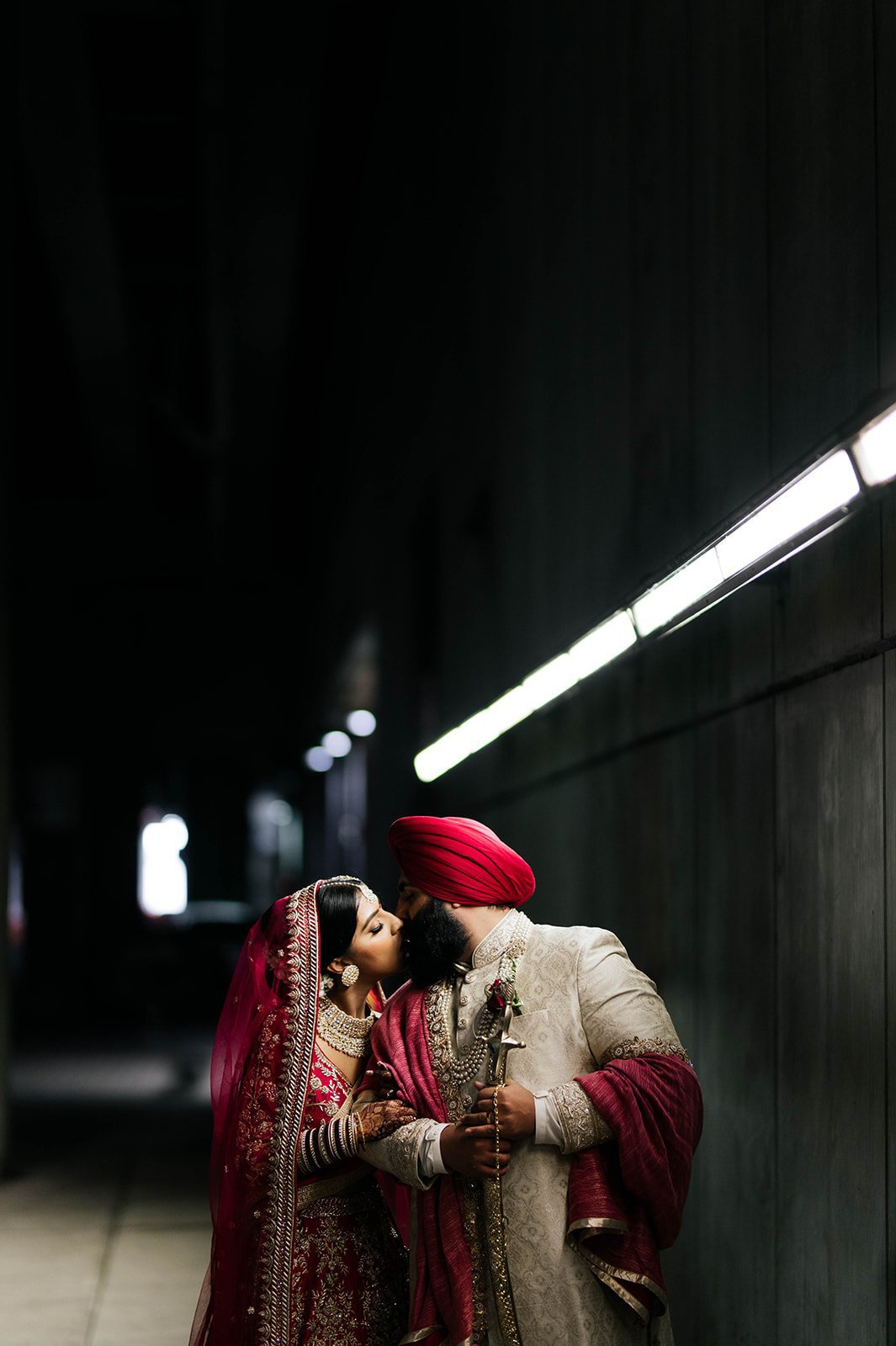 An Indian couple kiss in a cinematic backlit photo in a tunnel under vancouver, BC. 