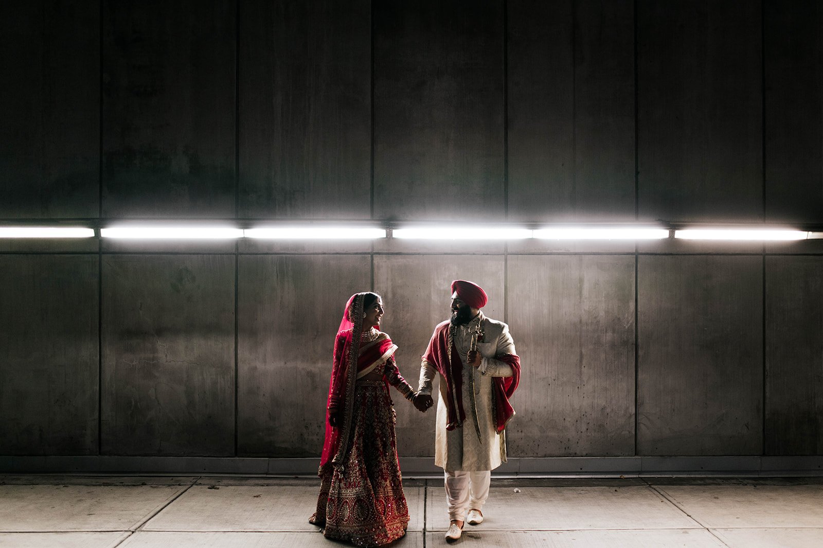 An Indian couple hold hands in a cinematic backlit photo in a tunnel under vancouver, BC. 