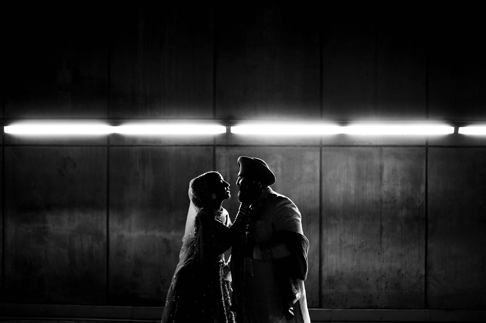 An Indian couple embrace in a cinematic backlit photo in a tunnel under vancouver, BC. 
