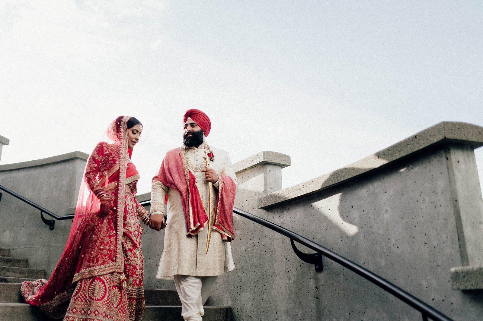 An Indian couple in traditional wedding outfits makes their way down stairs in Vancouver BC. 