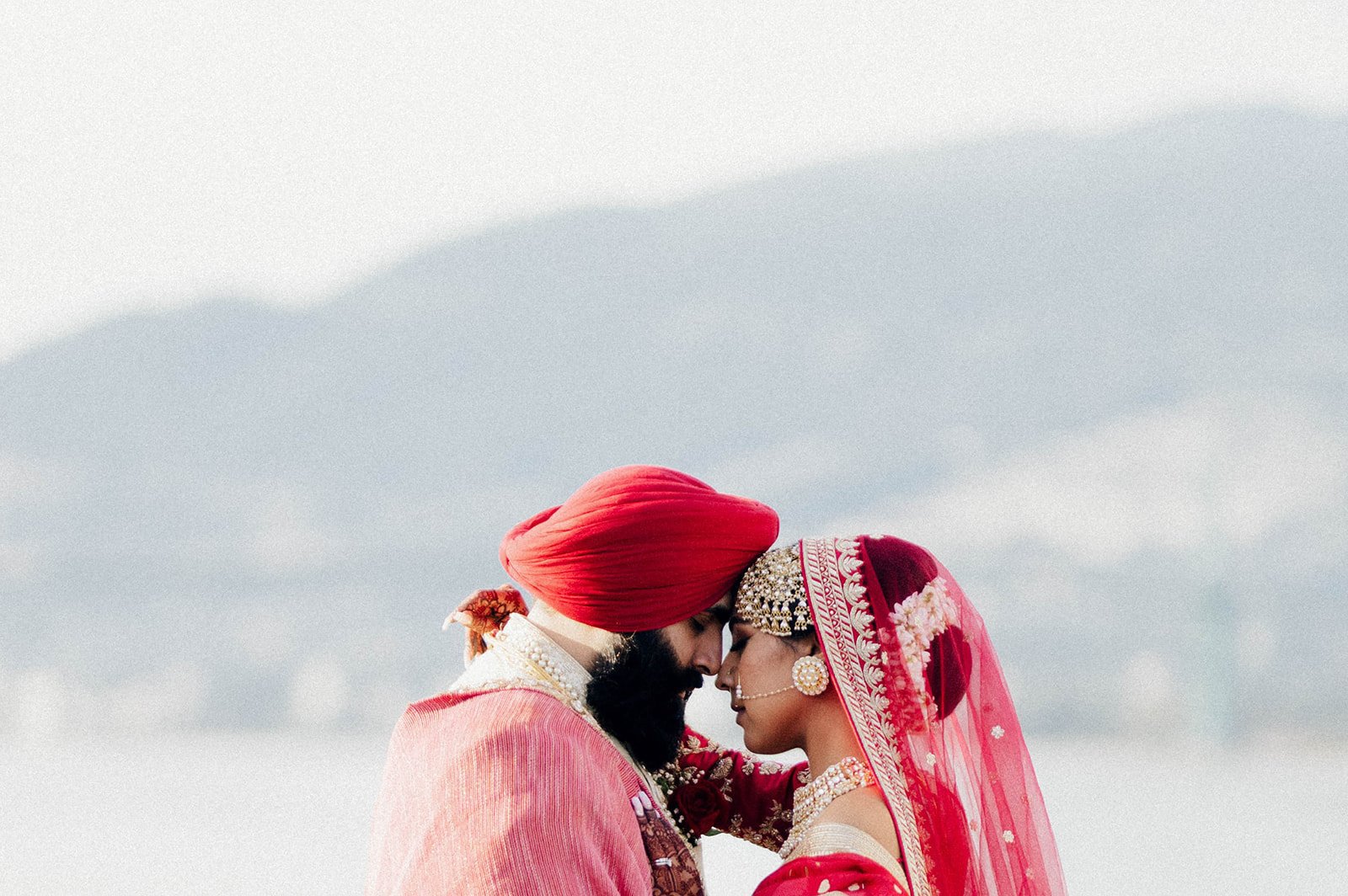 A beautiful Indian couple in bright red bump foreheads in front of the north shore in vancouver BC 