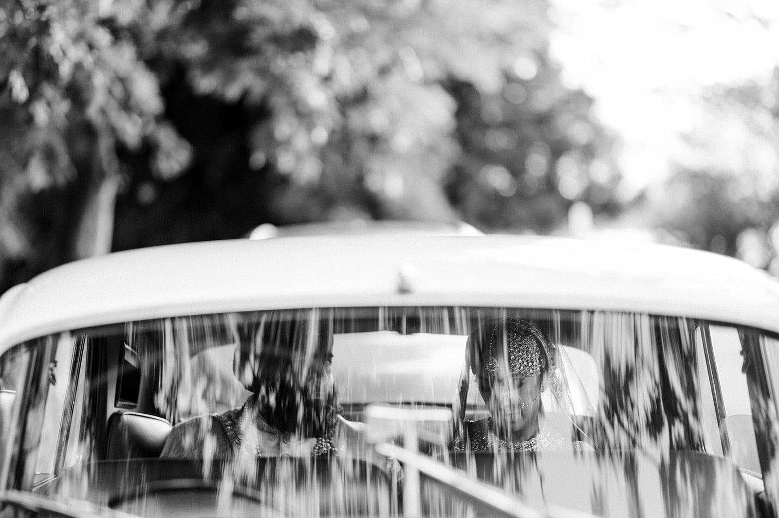 An artsy photo of an Indian couple through the window of an vintage car in Vancouver Bc.