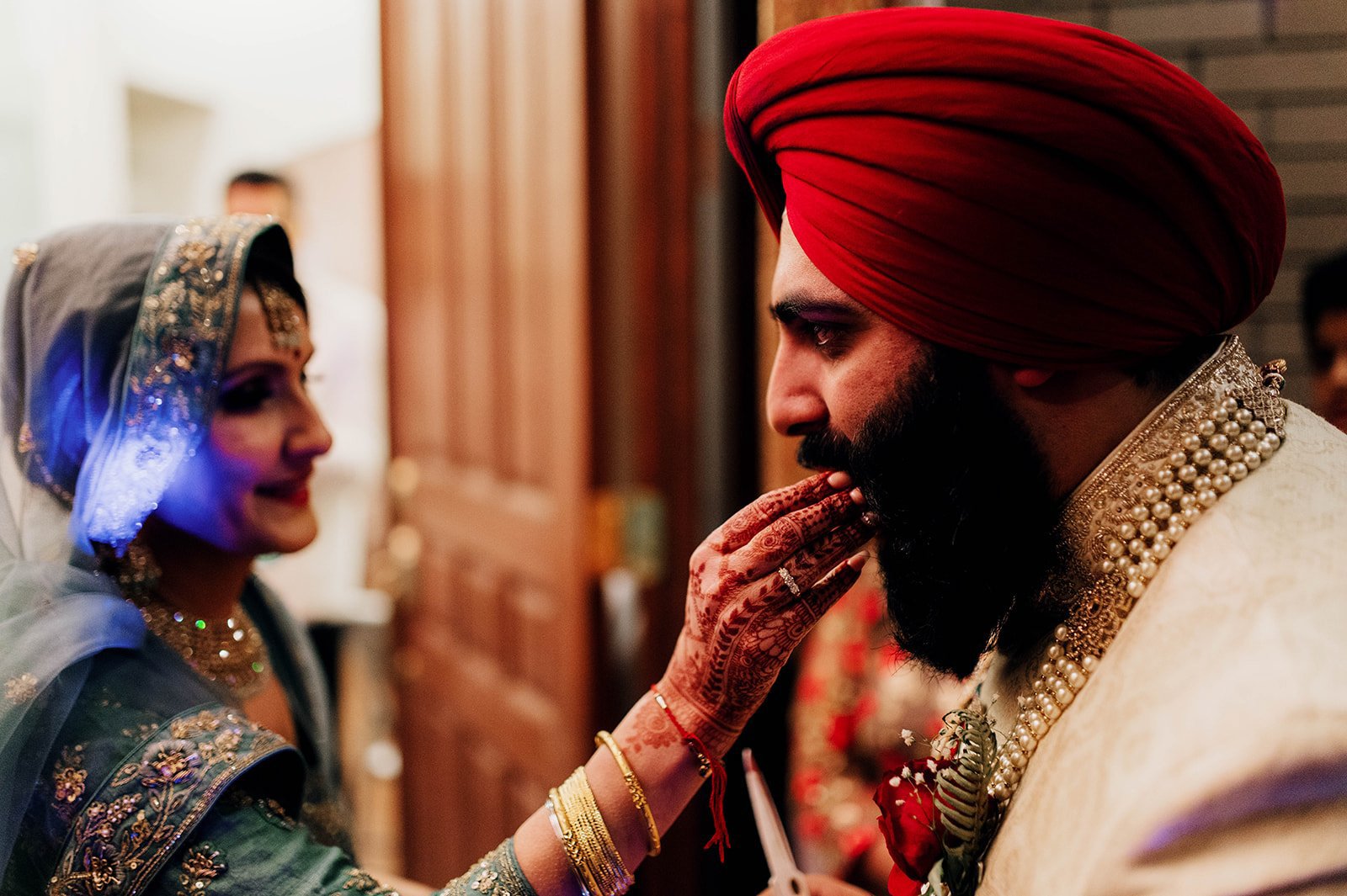 An indian woman feeds a groom as he ceremonially enters the brides house. 