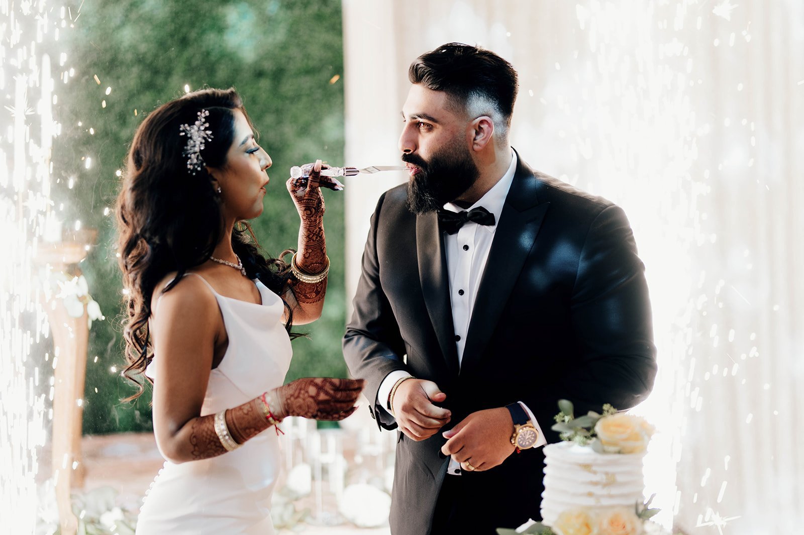 An indian bride feeds her groom some wedding cake.