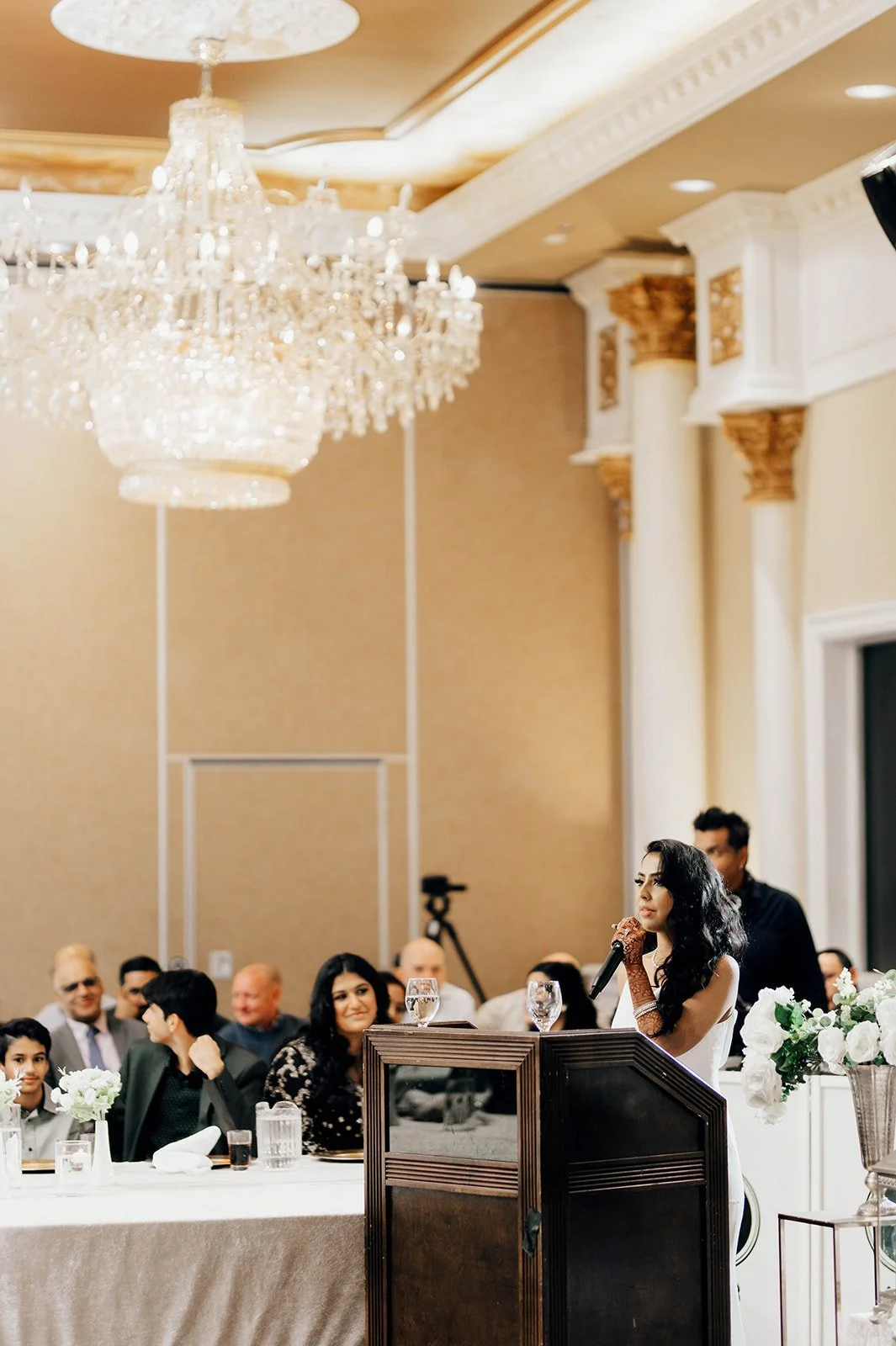 An Indian bride gives a speech in a reception ballroom..