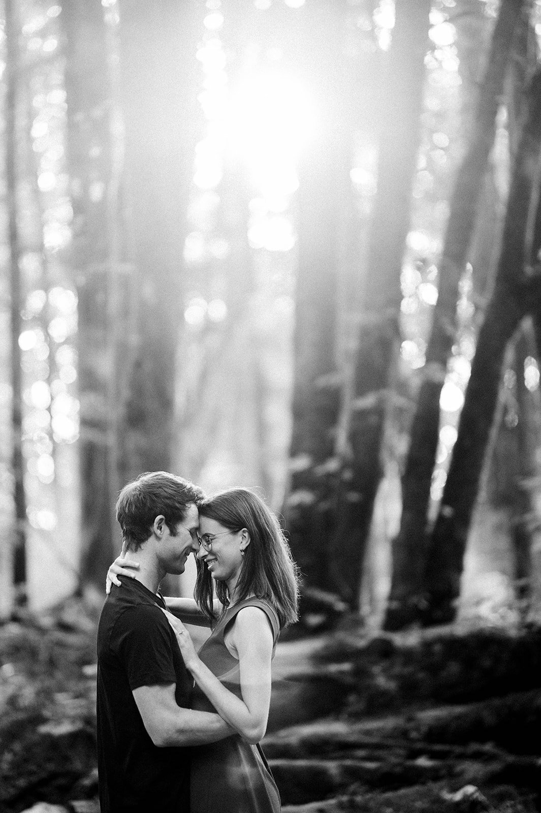 A bride rests her head against her fiancee as they enjoy a quiet moment in the woods during sunset in Stanley Park.