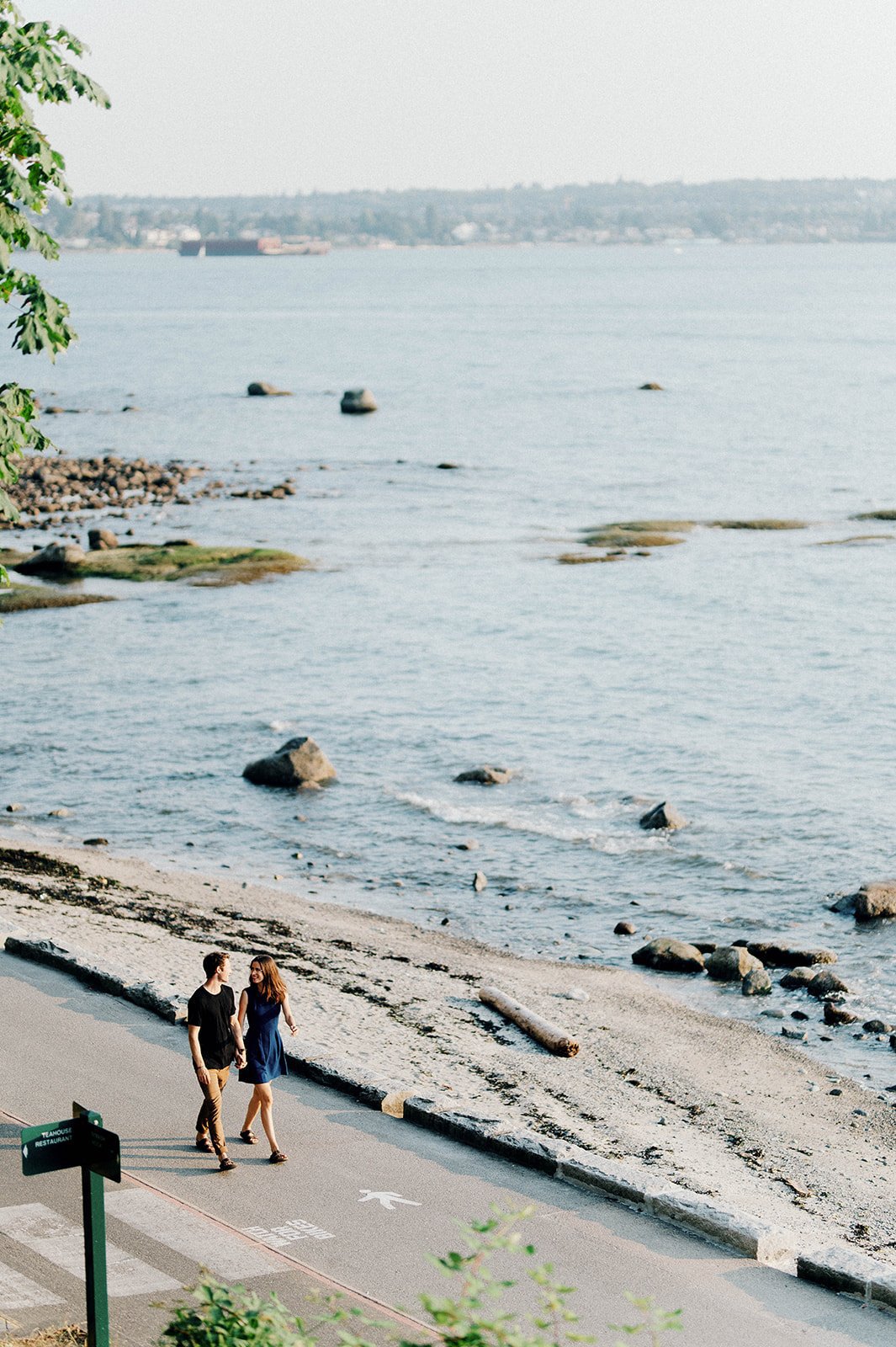 A handsome couple stroll on the seawall at English Bay on a clear sunny day in Vancouver BC.