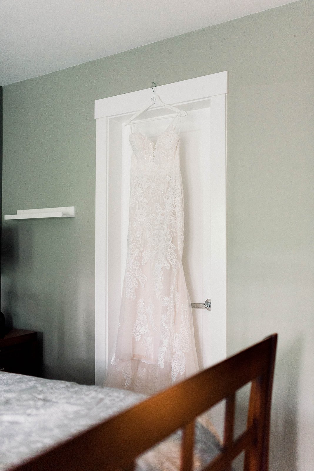 elegant wedding gown hanging from a doorway on the morning of a wedding