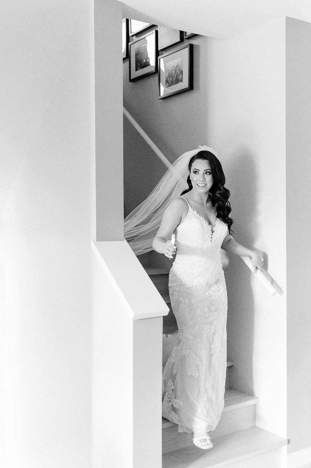Bride coming down the stairs in her wedding gown and veil on the morning of her wedding in Vancouver, BC.