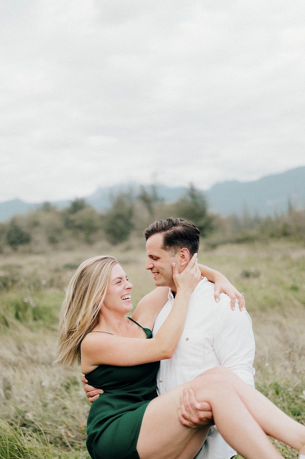 A man twirls around his fiancee in a grassy field in Squamish, BC.