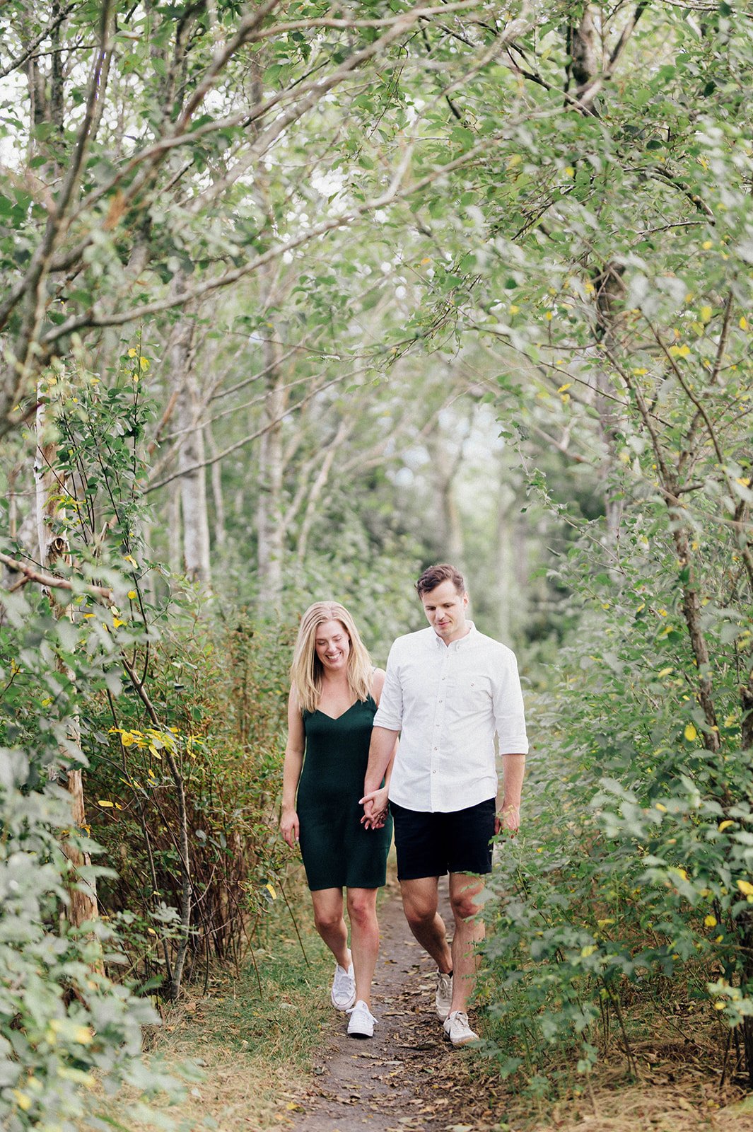 A young man and woman walk though a lightly wooded path in Squamish, BC.