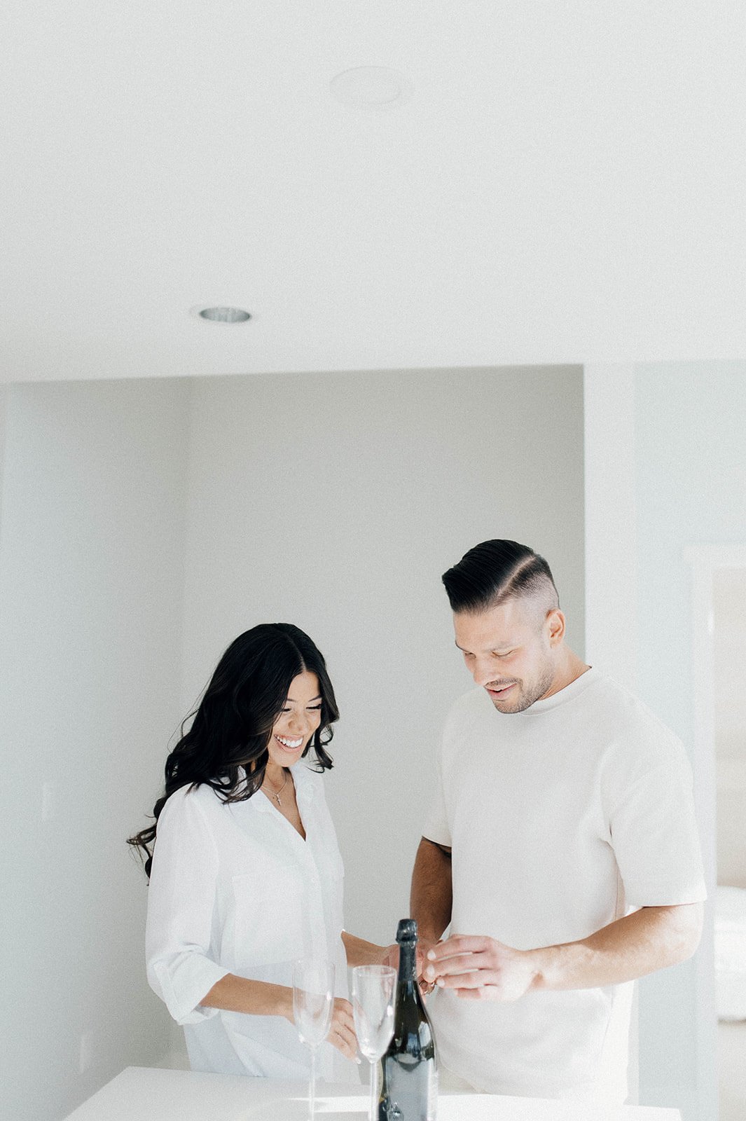 Couple opening champagne in their Vancouver apartment for their engagement session.