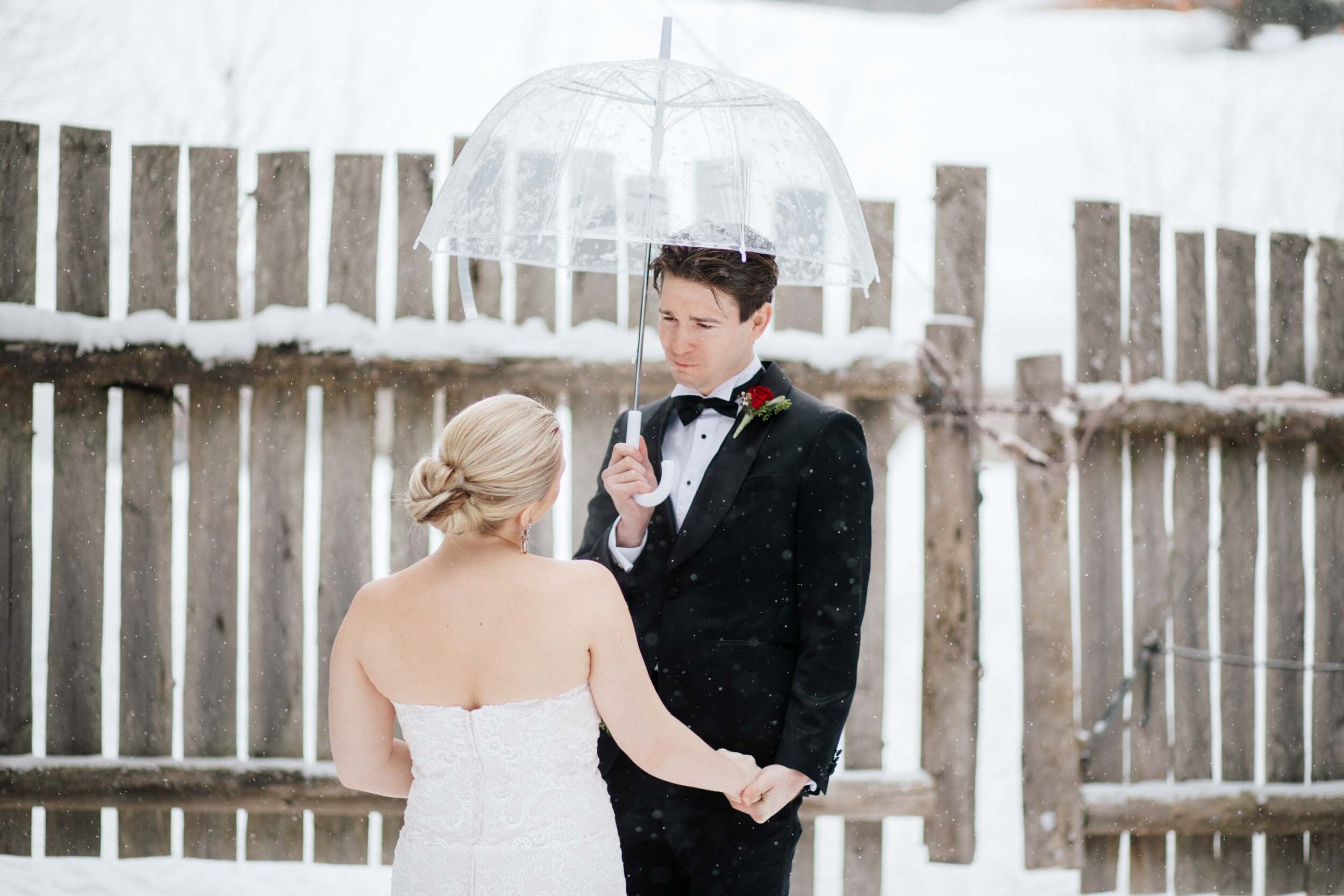 An emotion groom holds his brides hand as they stand in the snow in Whistler, BC.