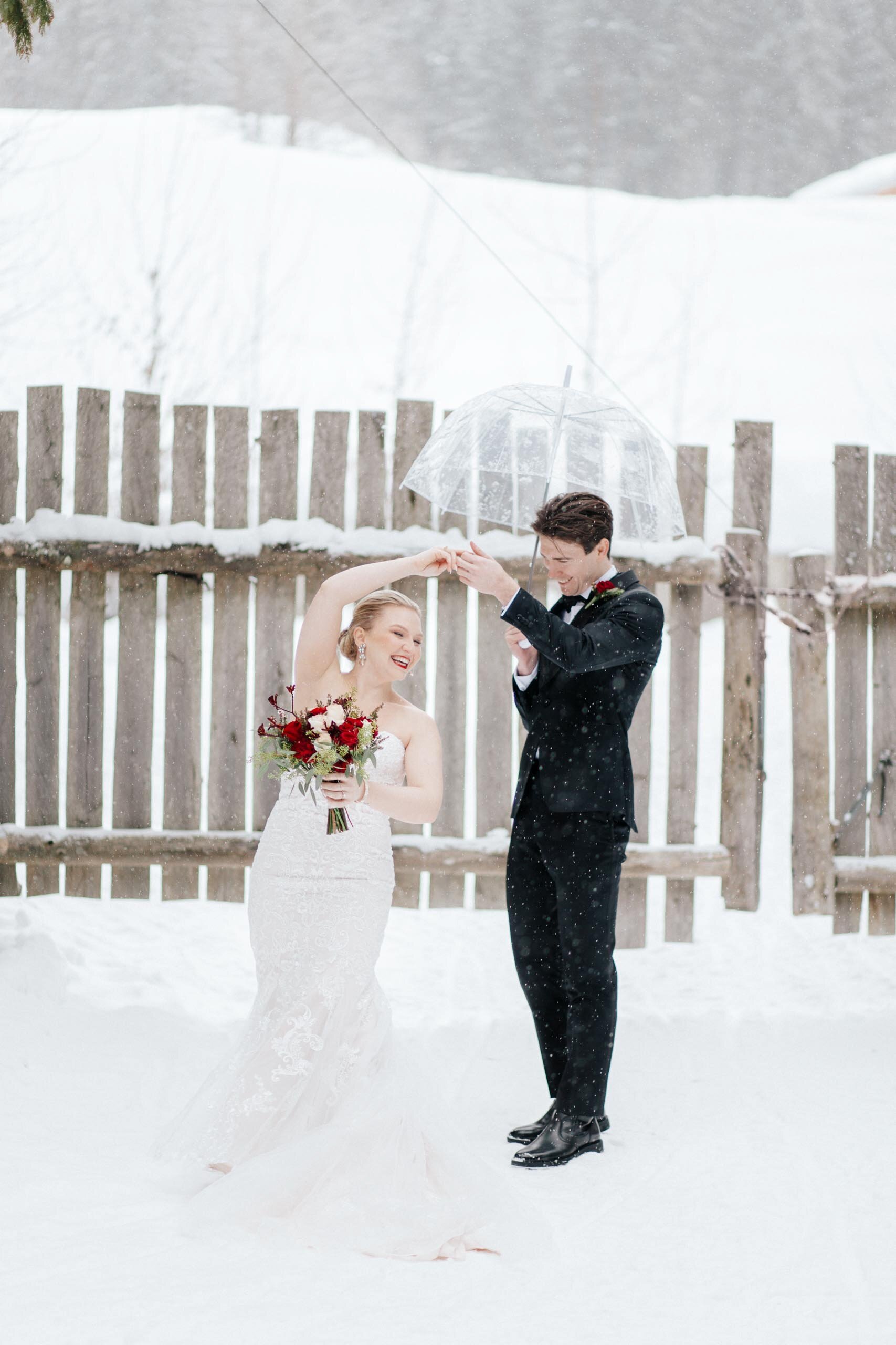A elegant bride with a deep red bouquet spins in the snow in Whistler, BC.
