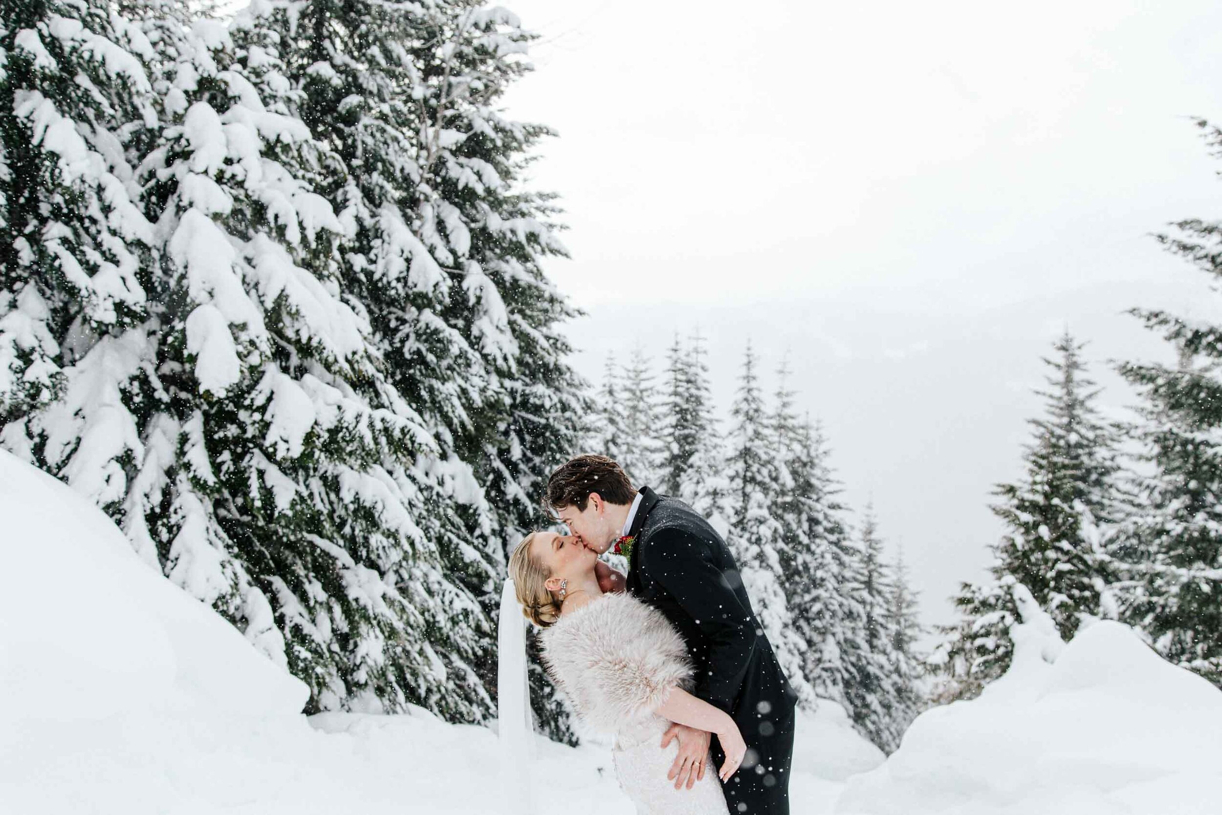 A bride and groom share their first kiss in the snow during their Whister wedding. 