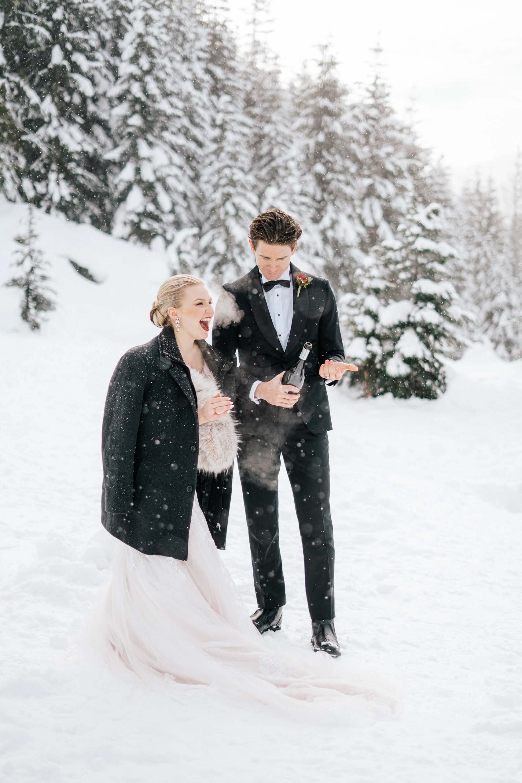 A chilly bride and groom pop champagne in the snow during their outdoor wedding. 